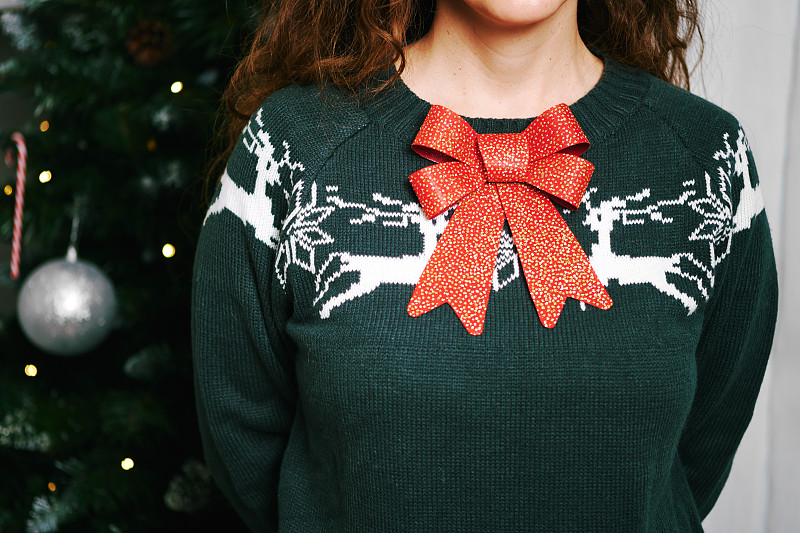 一个穿着绿色圣诞毛衣的白人年轻女子的特写图片下载