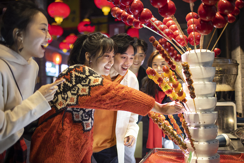 年轻朋友们逛街吃冰糖葫芦图片下载