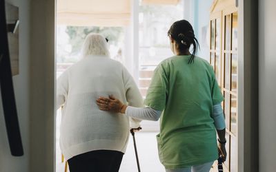 A person with a hip replacement is escorted by a caregiver