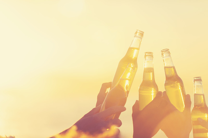 日落时分,一群年轻人在海滩上聚会。图片下载