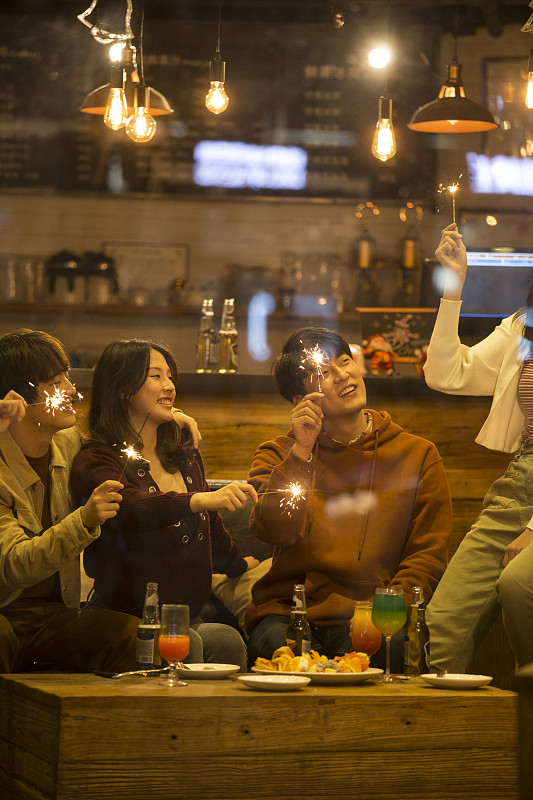 四个青年男女一起在酒吧聚会嬉戏放烟花欢度圣诞节图片下载