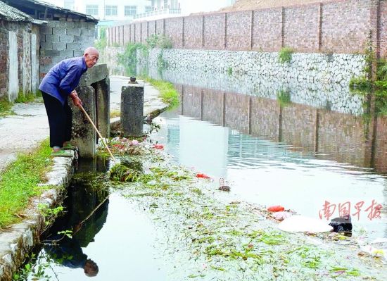 灵渠大湾陡附近，一堵围墙紧逼灵渠。89岁老人唐资元正在该处打捞水中的垃圾。南国早报记者郭燕群 邓振福 图