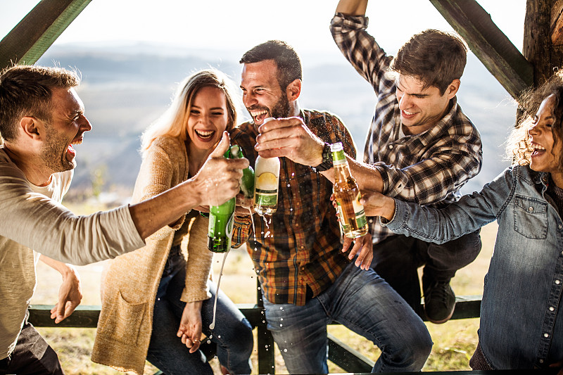 一群欢快的朋友在露台上喝啤酒玩得开心。图片下载