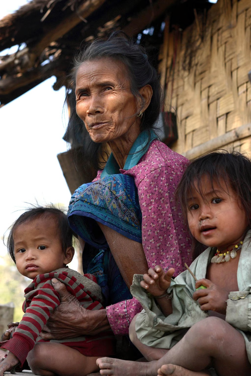 (图为 2005 年,老挝一座因水电站建设而被淹没的村庄内,一位老挝老妇人与她的孙辈。来源:法新社)