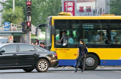 5月9日，朝阳路，一位闯红灯的市民被穿过路口的汽车“截停”在斑马线上。新京报记者 薛? 摄