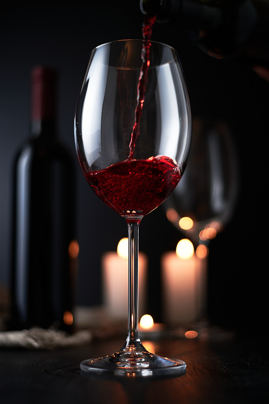 将红酒倒入深色背景的酒杯中,静物图片下载