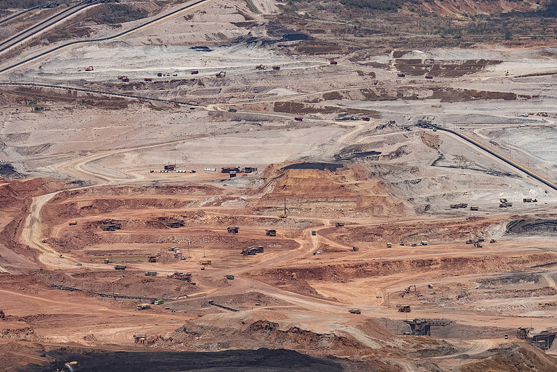 大型露天矿场的鸟瞰图，展示了输送带和工业机器正在开采土壤和矿物。图片下载